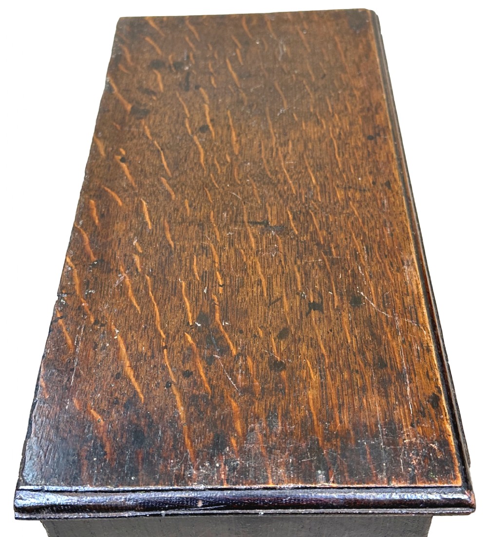 A dark oak miniature kneehole desk featuring a single top drawer over six side drawers and a central cupboard with a key and brass knobs. View V