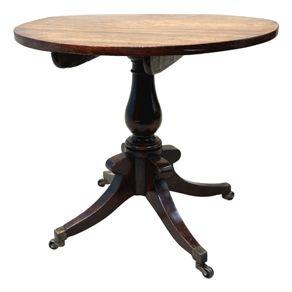 A Regency style miniature mahogany breakfast table with a circular tilt top, a central turned pedestal, and four splayed legs fitted with brass castors. View VII