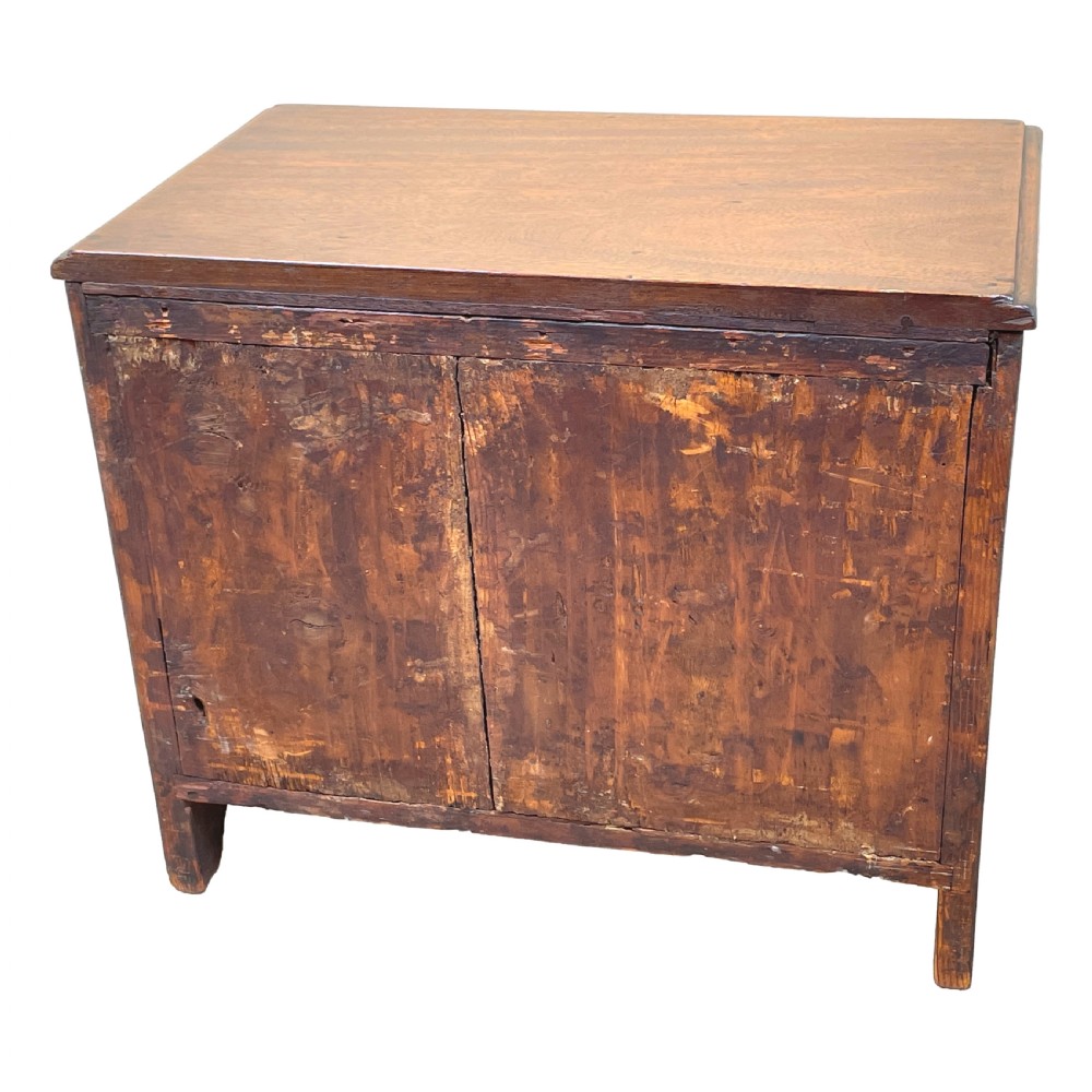 A small Georgian mahogany miniature chest featuring three drawers with brass knob handles, diamond-shaped escutcheons, and a shaped apron. View V