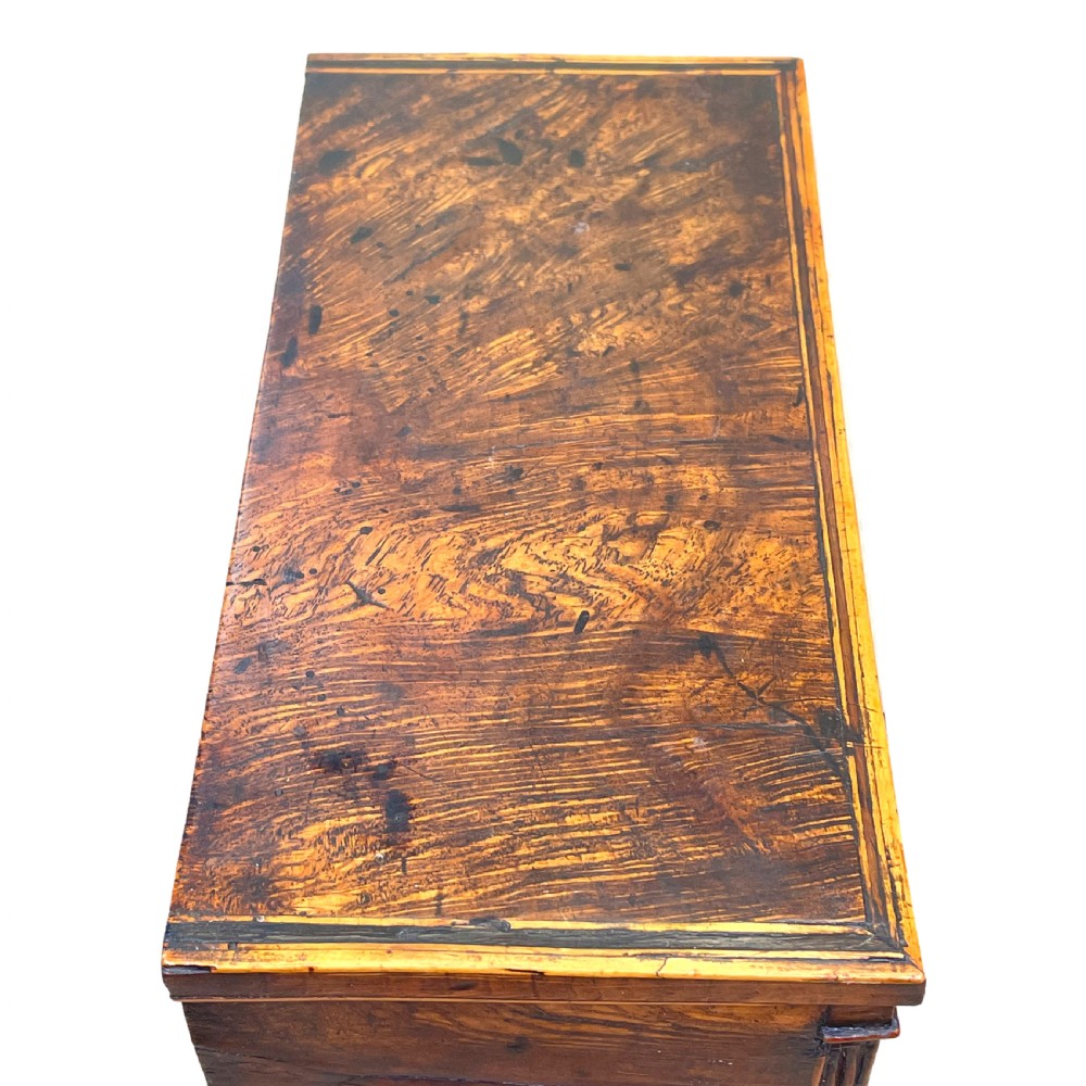 A Regency era miniature chest of drawers crafted from burr oak with geometric inlay, brass knobs, reeded pilasters, and small turned ball feet. View VI