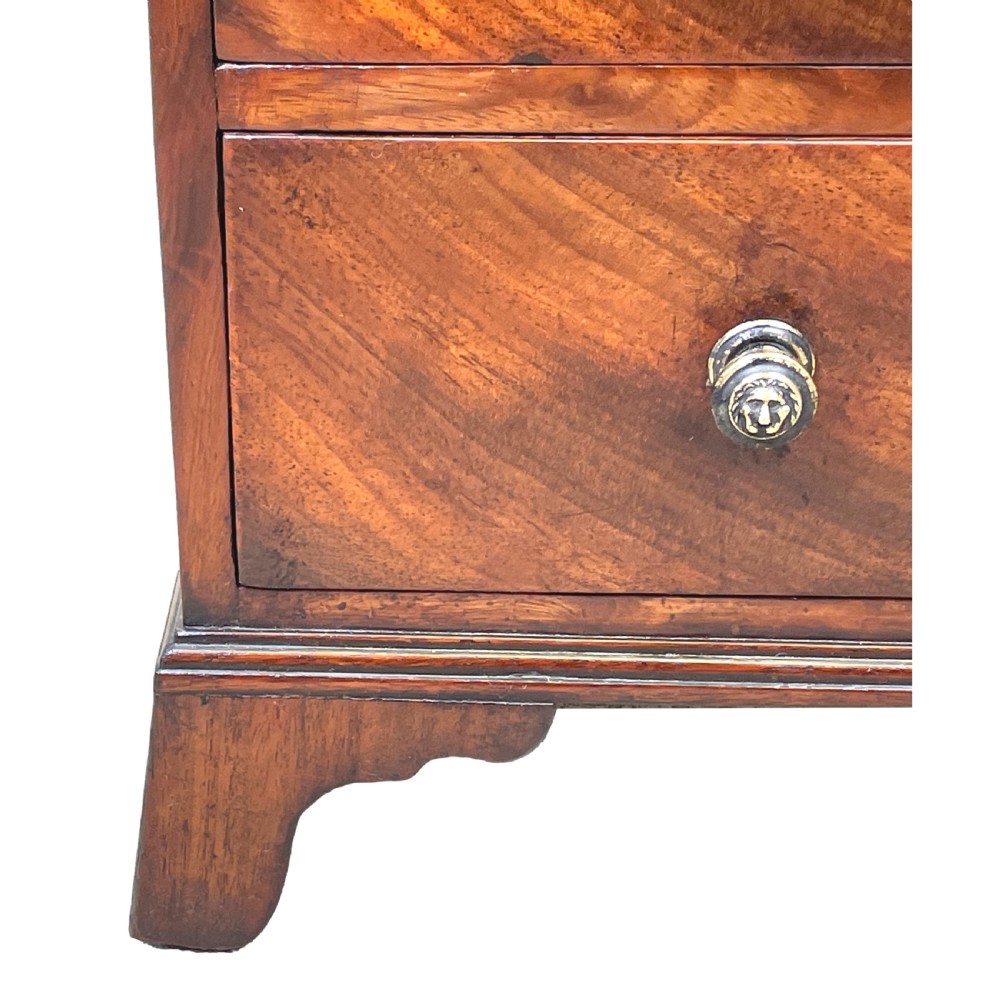 A Georgian miniature chest of drawers in flame mahogany featuring two short drawers over three long drawers with turned knobs and bracket feet. View II