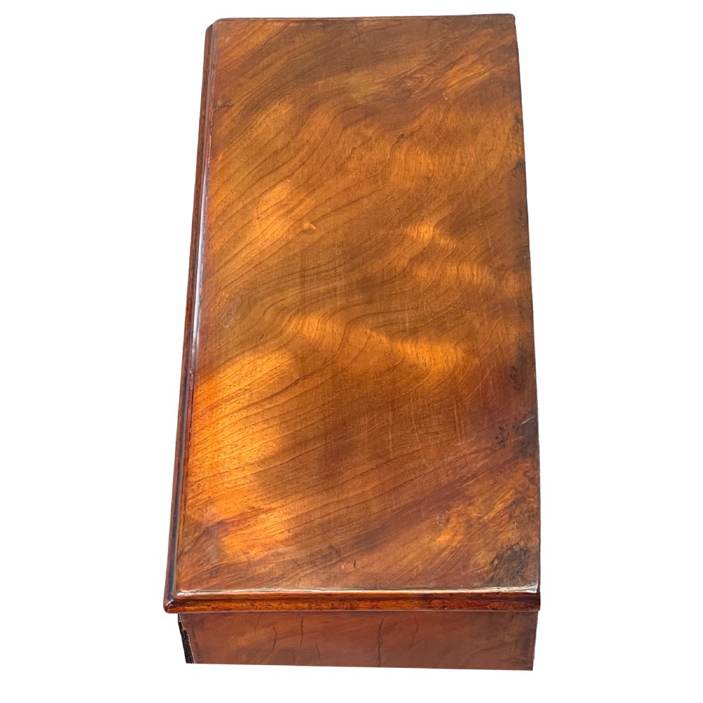 A Georgian miniature chest of drawers in flame mahogany featuring two short drawers over three long drawers with turned knobs and bracket feet. View V