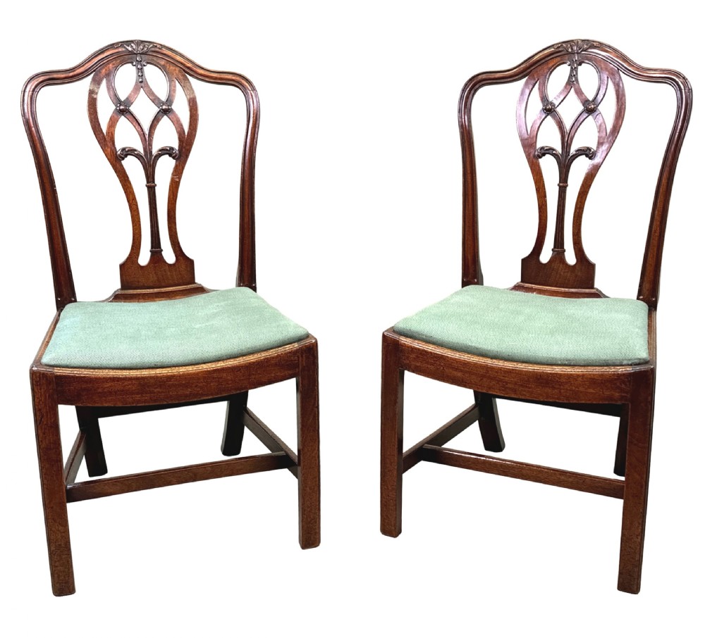 A pair of 18th-century Georgian mahogany side chairs featuring pierced back splats, serpentine top rails, and light green upholstered drop-in seats. View X