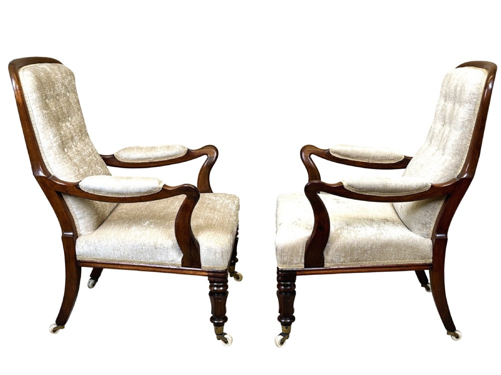A pair of 19th-century rosewood library armchairs with button-backed neutral beige upholstery and turned legs on brass casters. View II