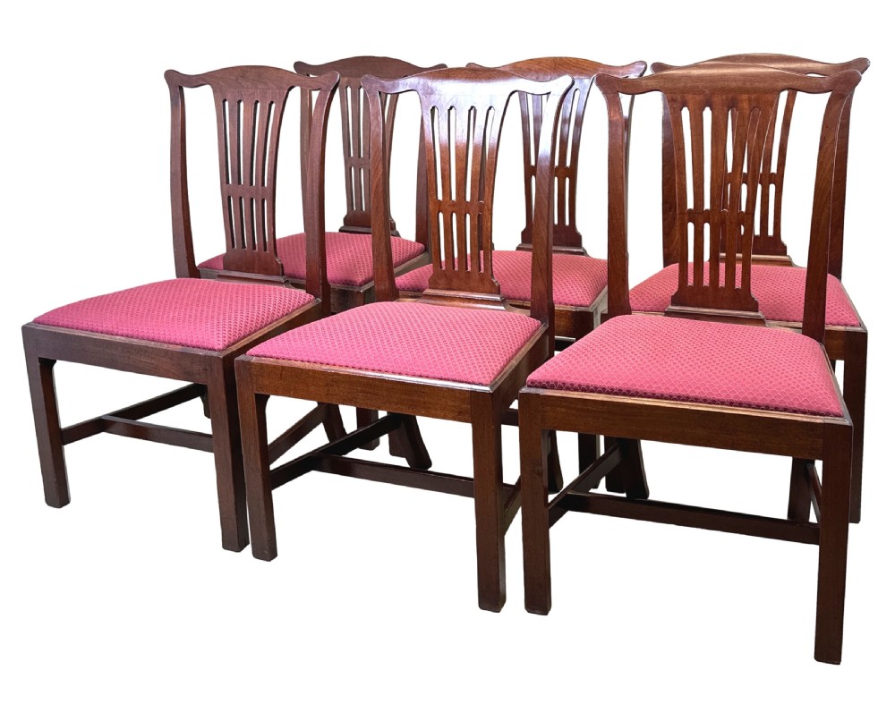 A set of six Chippendale period mahogany dining chairs with vertical slat splat backs, straight legs, and red textured upholstered seats.