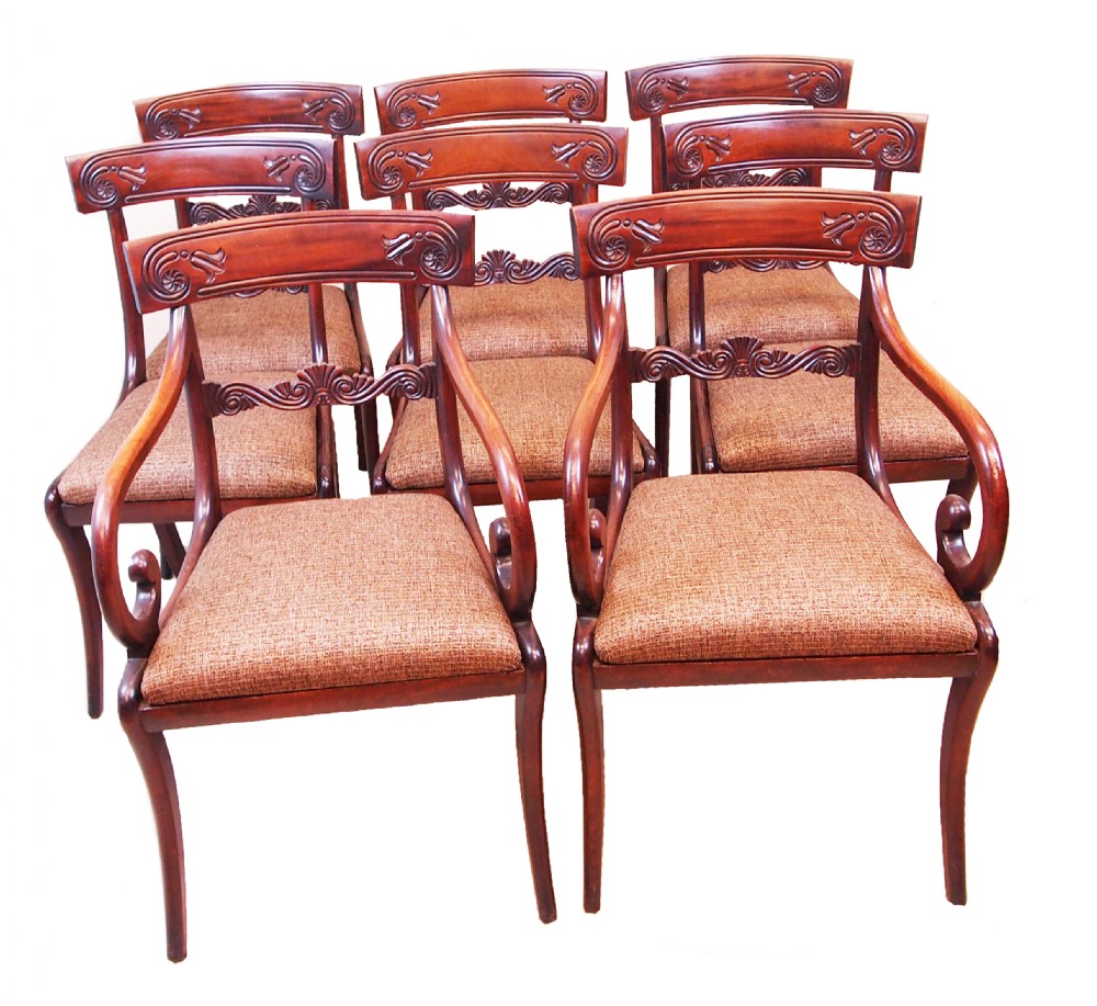 A set of eight Regency period mahogany dining chairs, including two carver armchairs and six side chairs, featuring carved bar backs and upholstered seats.