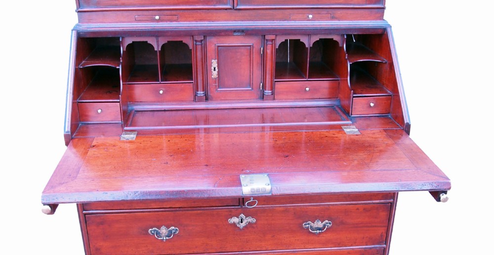 An early 18th-century walnut bureau bookcase featuring arched mirrored upper doors with finials above a slant-front writing desk and graduated drawers on bracket feet. View V