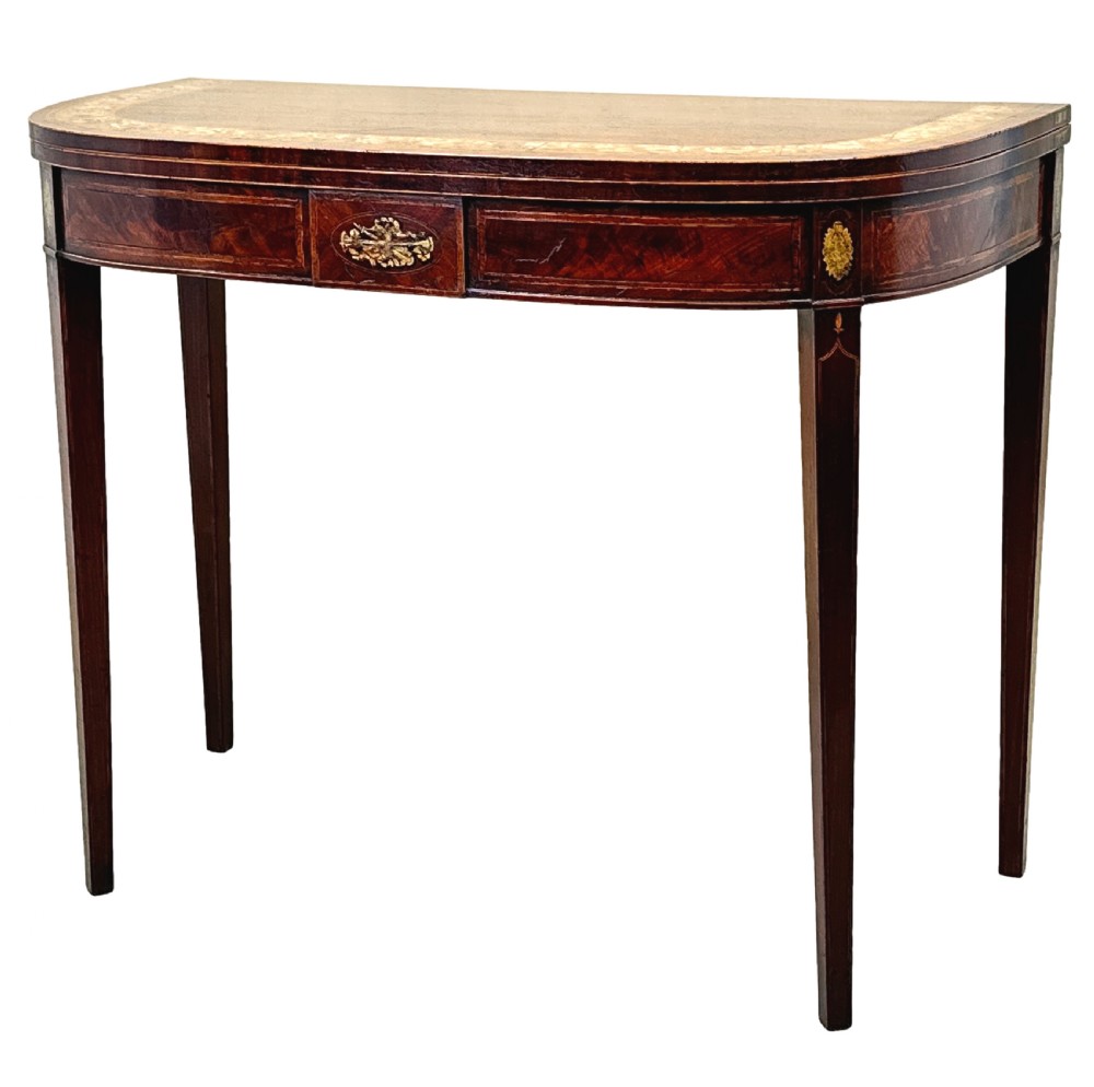 An eighteenth-century Georgian demilune mahogany tea table featuring decorative marquetry border, central brass mount, and tapered legs.