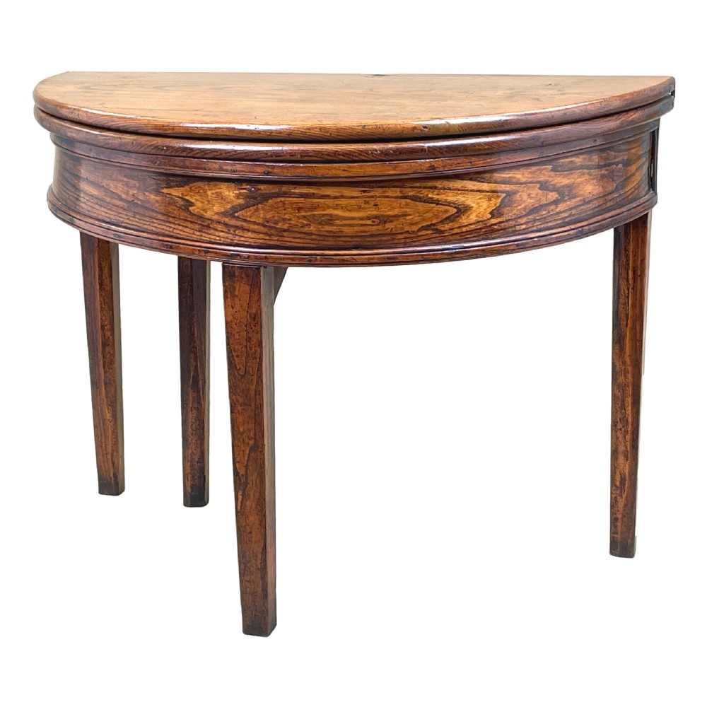 A Georgian elm demi-lune tea table displaying rich wood grain, a fold-over top, and square tapered legs.
