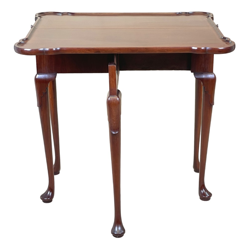 An 18th-century walnut tea table featuring a fold-over rectangular top with shaped corners, elevated on slender cabriole legs with pad feet. View VI