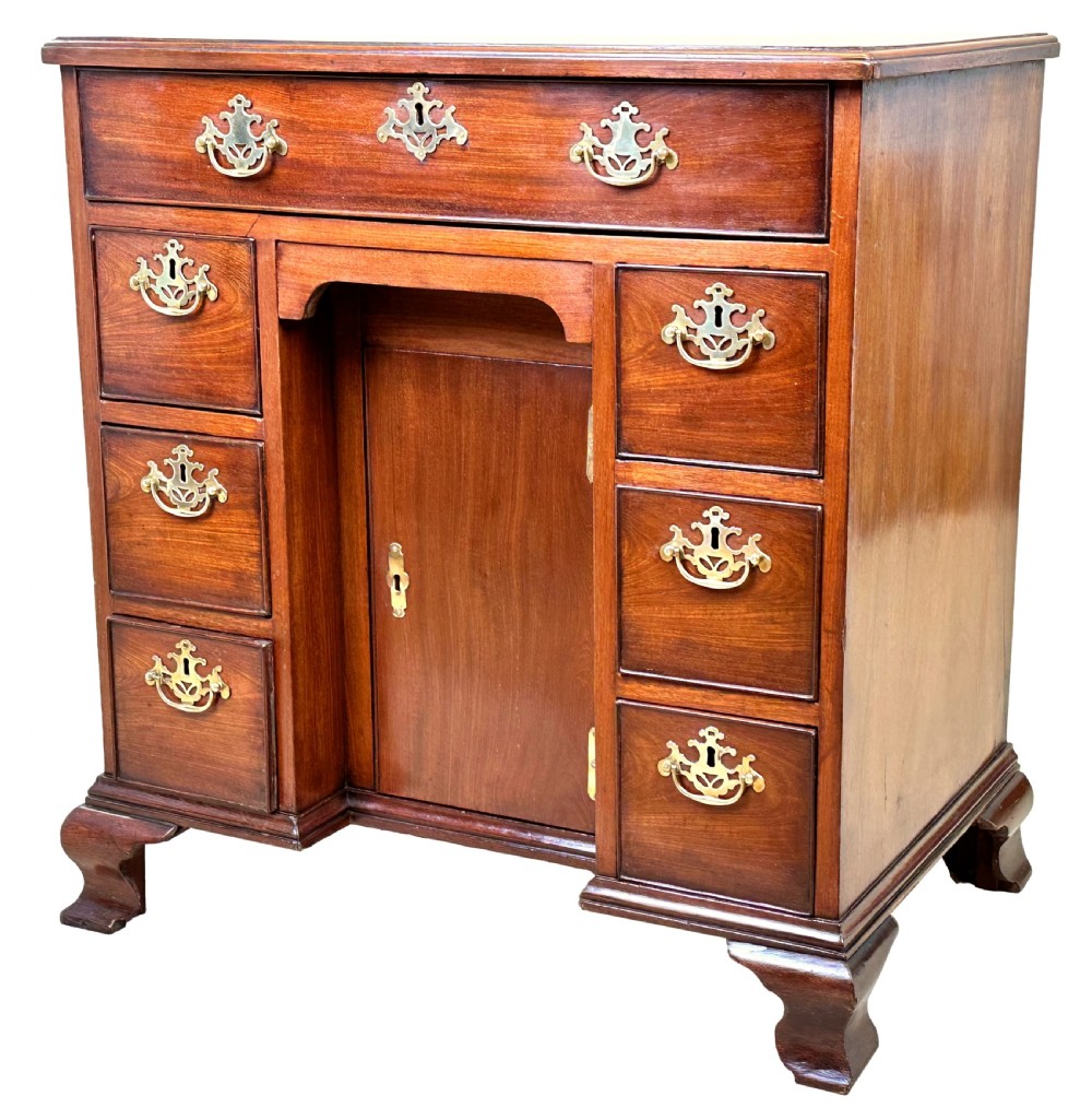 A Georgian mahogany kneehole desk featuring a long top drawer, two side banks of three drawers, a central recessed cupboard, and decorative brass handles. View II