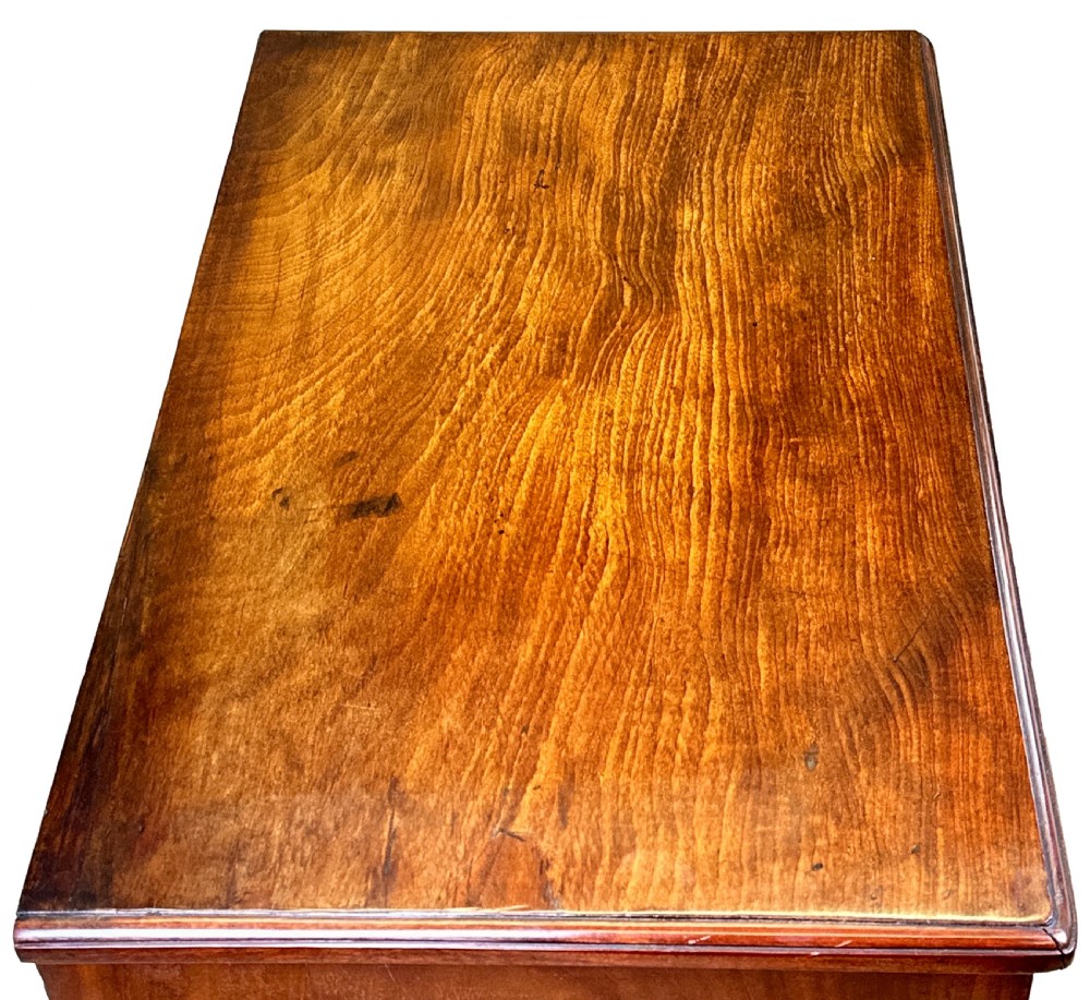 A Georgian mahogany kneehole desk featuring a long top drawer, two side banks of three drawers, a central recessed cupboard, and decorative brass handles. View III