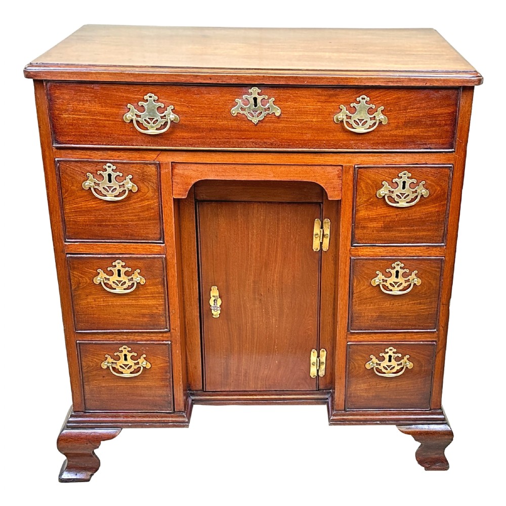 A Georgian mahogany kneehole desk featuring a long top drawer, two side banks of three drawers, a central recessed cupboard, and decorative brass handles. View XII