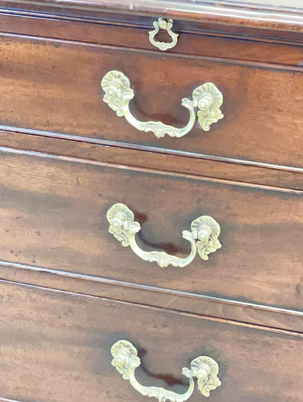 An eighteenth-century Georgian mahogany chest of drawers featuring four graduated drawers, brass swan-neck handles, and bracket feet. View VI
