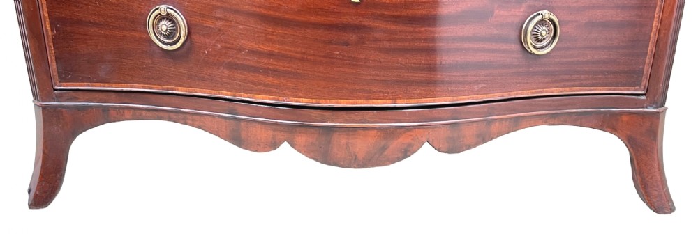 A Georgian style mahogany chest of drawers featuring a serpentine front, four graduated drawers with brass ring handles, and bracket feet. View IX