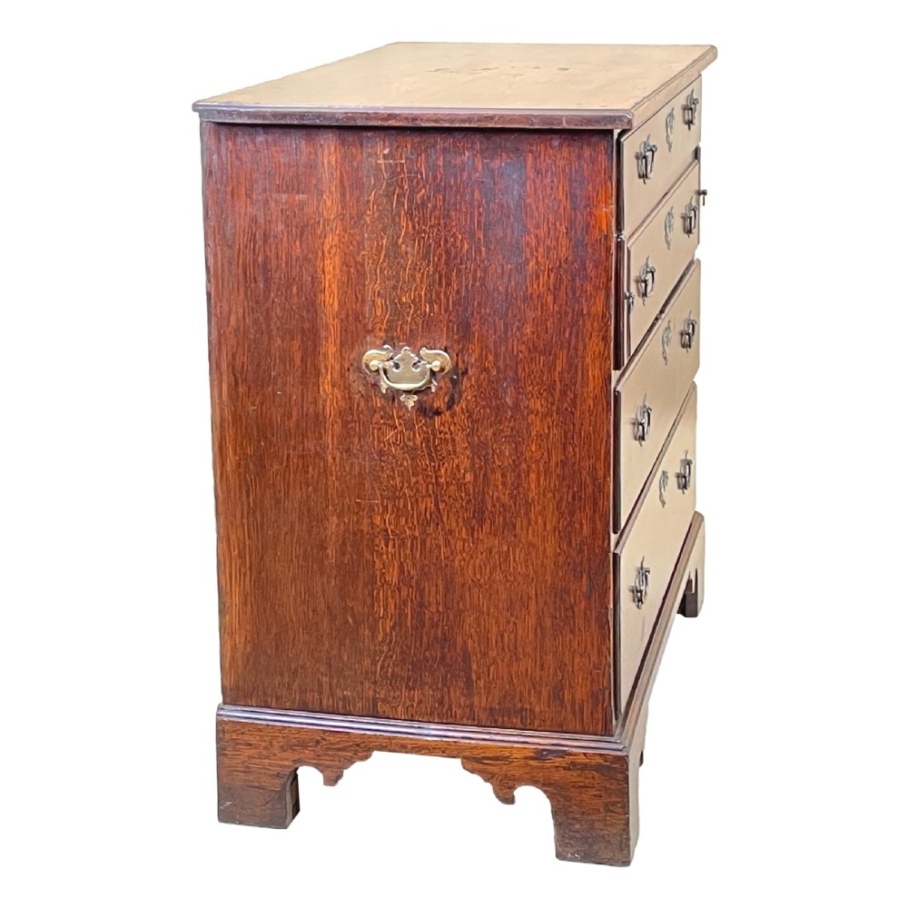 An eighteenth-century oak bachelors chest featuring four drawers with brass drop handles, escutcheons, a pull-out brushing slide, and bracket feet. View V