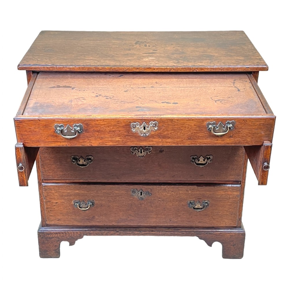 An eighteenth-century oak bachelors chest featuring four drawers with brass drop handles, escutcheons, a pull-out brushing slide, and bracket feet. View VII