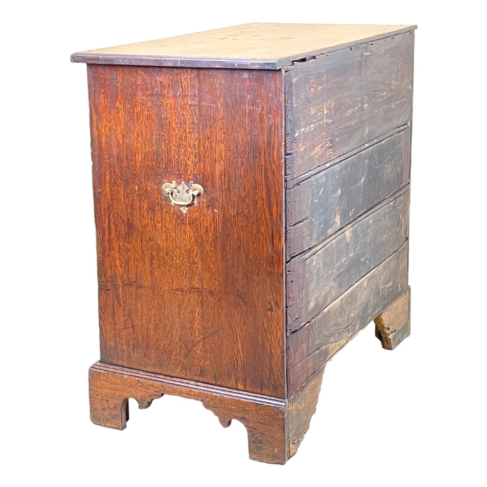 An eighteenth-century oak bachelors chest featuring four drawers with brass drop handles, escutcheons, a pull-out brushing slide, and bracket feet. View IX