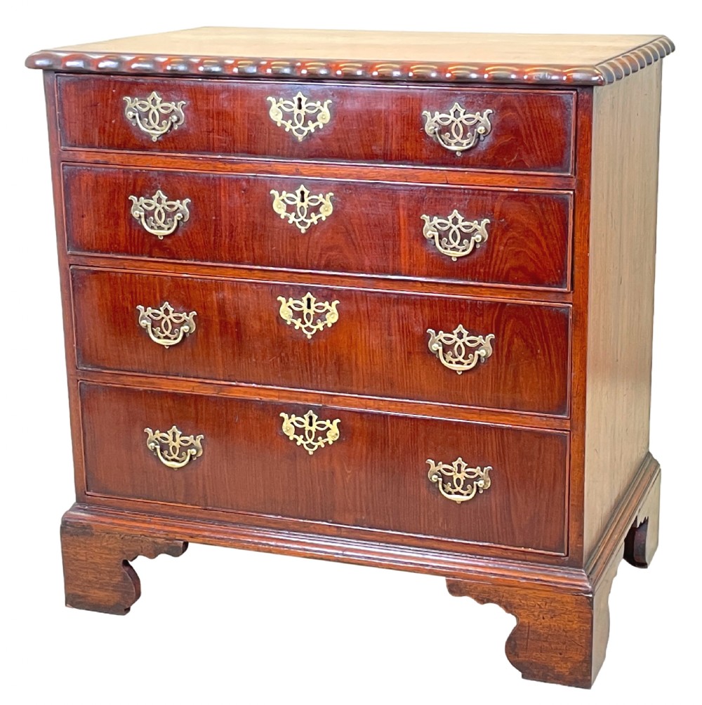 An 18th-century walnut chest of drawers featuring four graduated drawers with ornamental brass handles and escutcheons resting on shaped bracket feet.