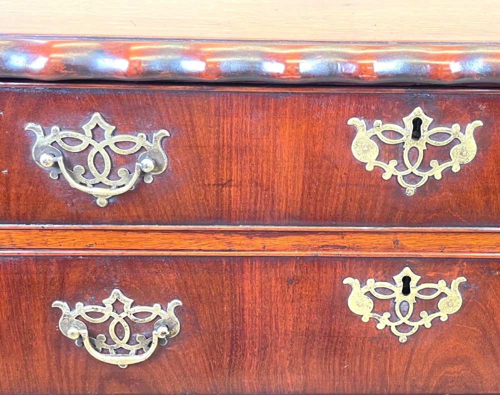An 18th-century walnut chest of drawers featuring four graduated drawers with ornamental brass handles and escutcheons resting on shaped bracket feet. View VI