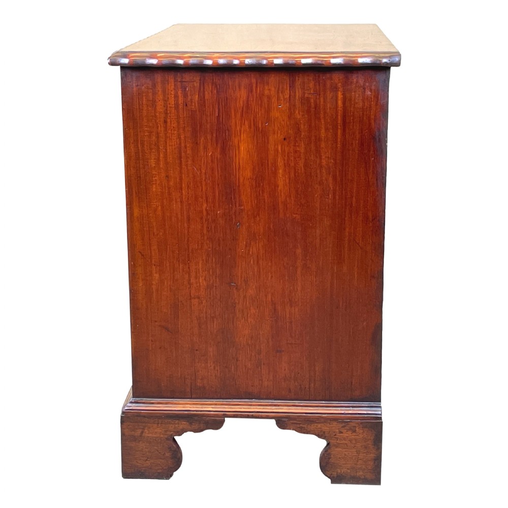 An 18th-century walnut chest of drawers featuring four graduated drawers with ornamental brass handles and escutcheons resting on shaped bracket feet. View VII