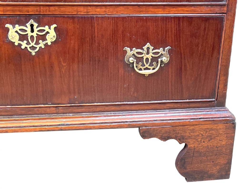 An 18th-century walnut chest of drawers featuring four graduated drawers with ornamental brass handles and escutcheons resting on shaped bracket feet. View XI