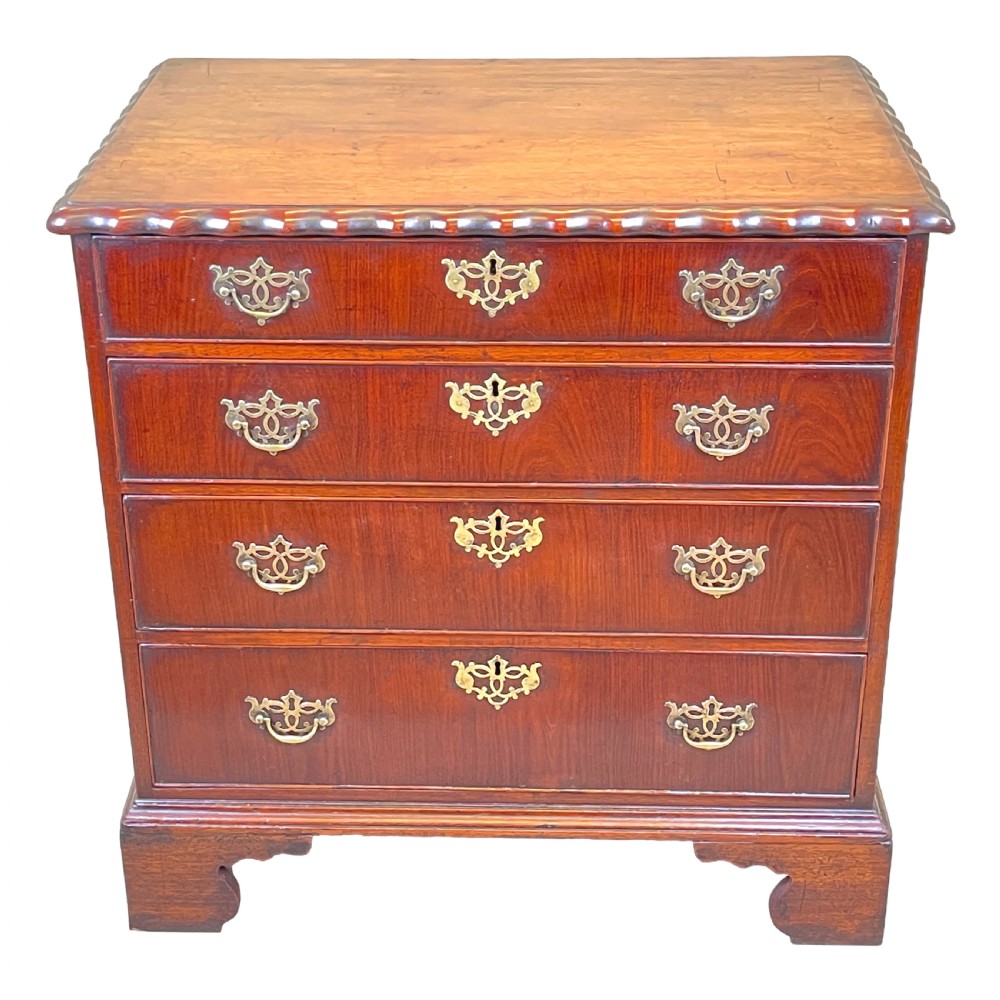 An 18th-century walnut chest of drawers featuring four graduated drawers with ornamental brass handles and escutcheons resting on shaped bracket feet. View XIV