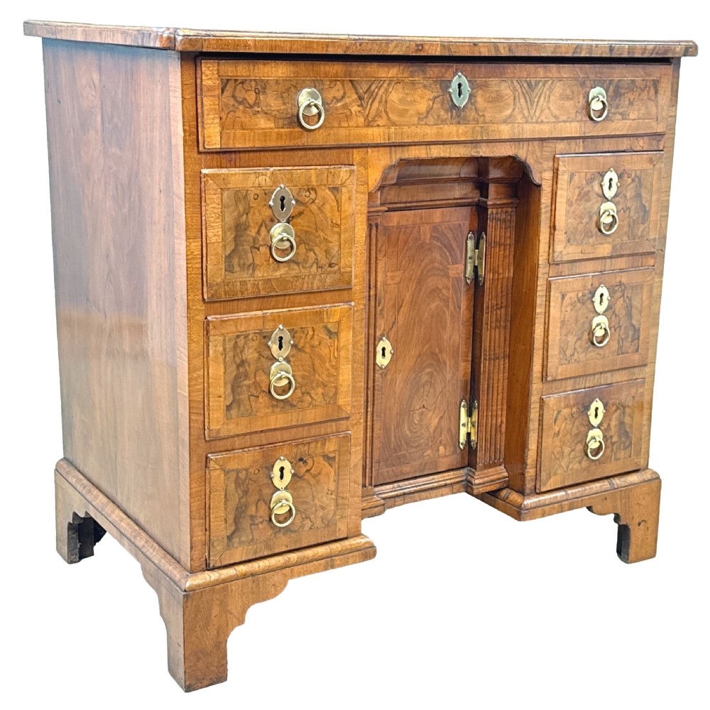 An 18th-century Georgian walnut kneehole desk featuring figured veneer drawer fronts, brass drop handles, and bracket feet. View VI