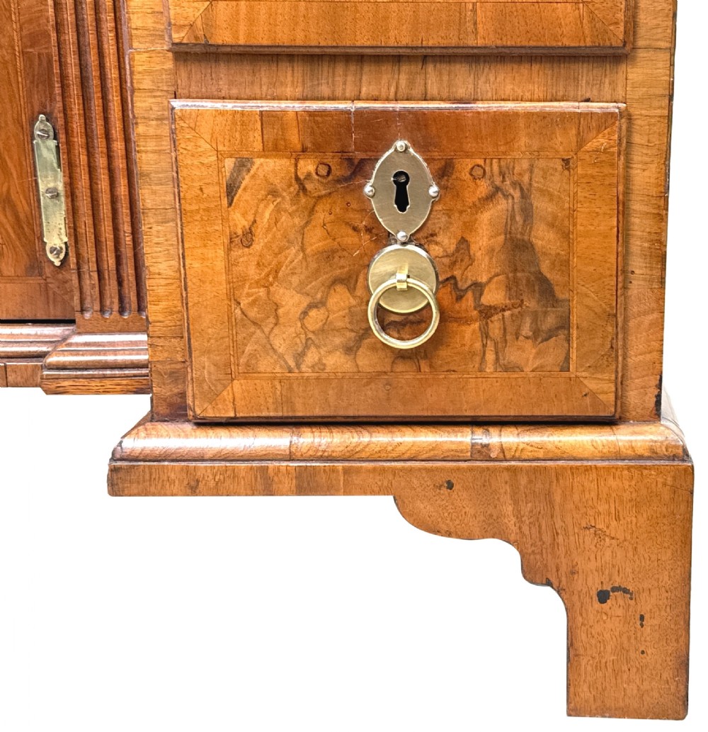 An 18th-century Georgian walnut kneehole desk featuring figured veneer drawer fronts, brass drop handles, and bracket feet. View XII