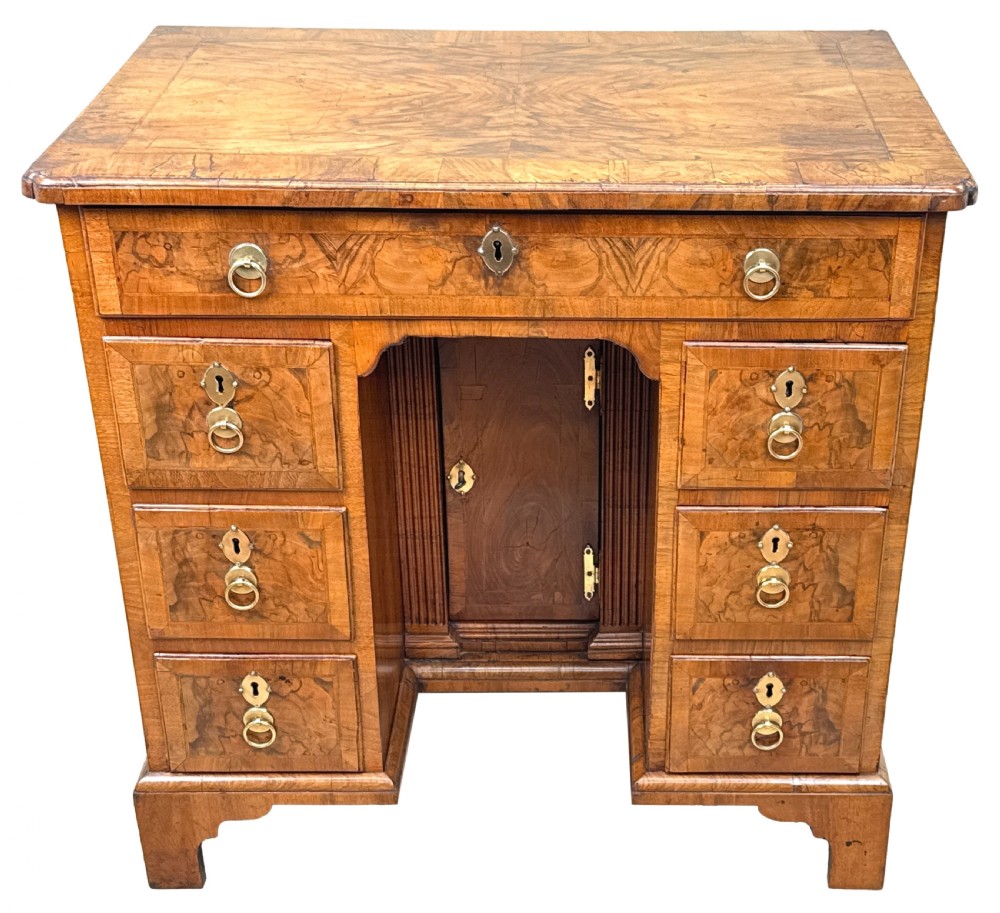 An 18th-century Georgian walnut kneehole desk featuring figured veneer drawer fronts, brass drop handles, and bracket feet. View XVI