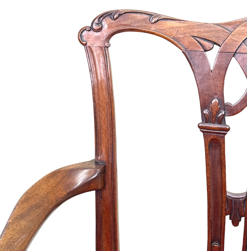 An 18th-century Chippendale style mahogany open armchair with a carved pierced back splat, curved arms, and red woven seat upholstery. View V