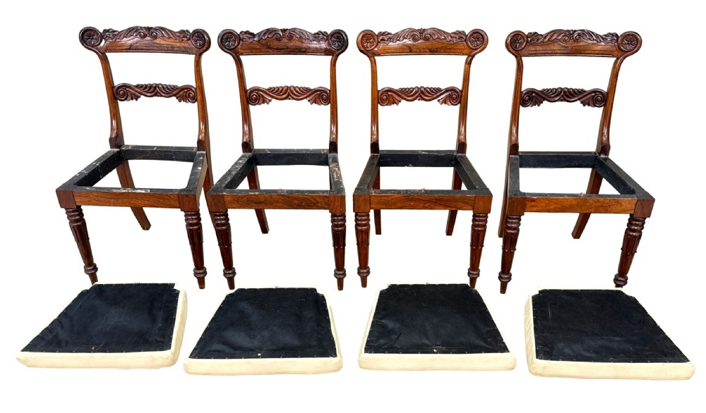 A set of ten Regency rosewood dining chairs featuring carved crest rails, scrolled mid-bars, turned front legs, and cream embroidered needlepoint seats. View VI