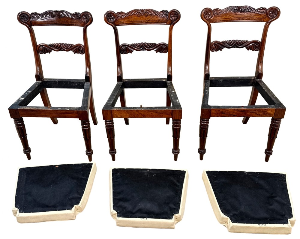 A set of ten Regency rosewood dining chairs featuring carved crest rails, scrolled mid-bars, turned front legs, and cream embroidered needlepoint seats. View XIII
