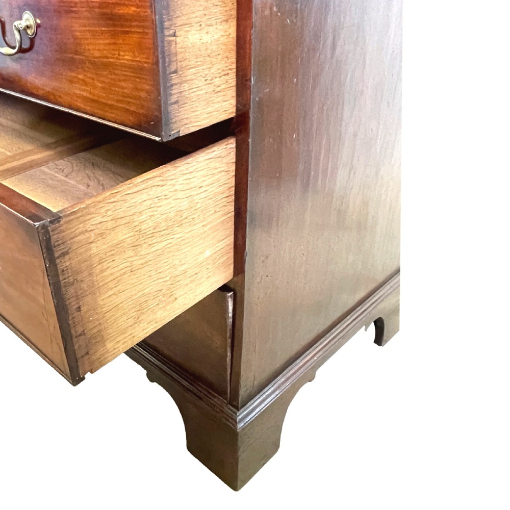A Georgian mahogany linen press featuring an upper cabinet with oval flame mahogany veneered panels above a chest with four drawers. View VII