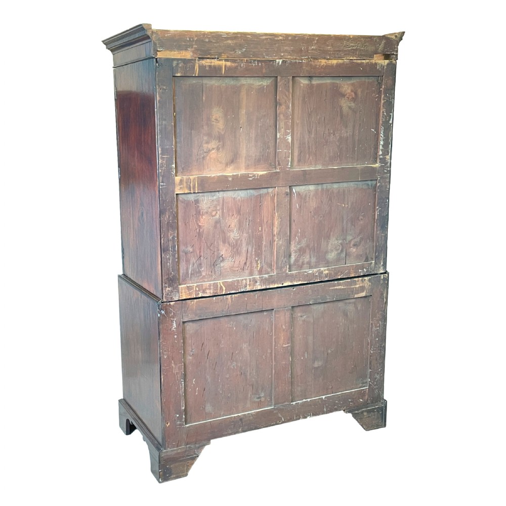 A Georgian mahogany linen press featuring an upper cabinet with oval flame mahogany veneered panels above a chest with four drawers. View IX