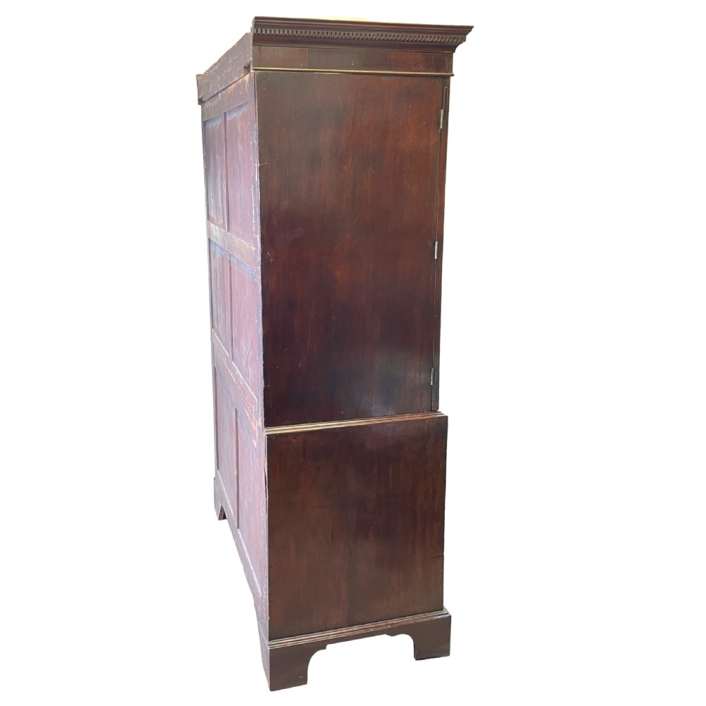 A Georgian mahogany linen press featuring an upper cabinet with oval flame mahogany veneered panels above a chest with four drawers. View X