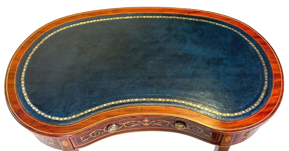 A nineteenth-century mahogany kidney-shaped writing table featuring foliate marquetry, a dark leather insert, and square tapered legs with brass castors. View II