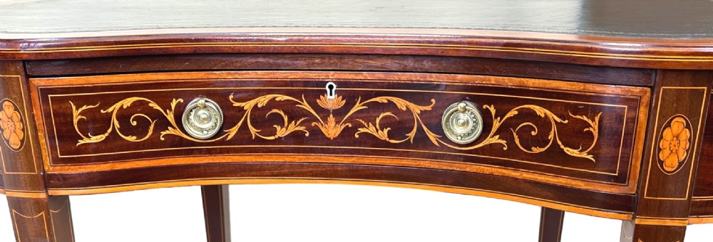 A nineteenth-century mahogany kidney-shaped writing table featuring foliate marquetry, a dark leather insert, and square tapered legs with brass castors. View V