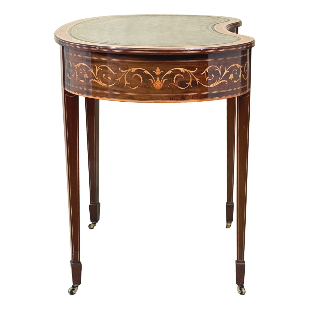 A nineteenth-century mahogany kidney-shaped writing table featuring foliate marquetry, a dark leather insert, and square tapered legs with brass castors. View X