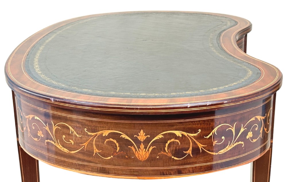 A nineteenth-century mahogany kidney-shaped writing table featuring foliate marquetry, a dark leather insert, and square tapered legs with brass castors. View XIII
