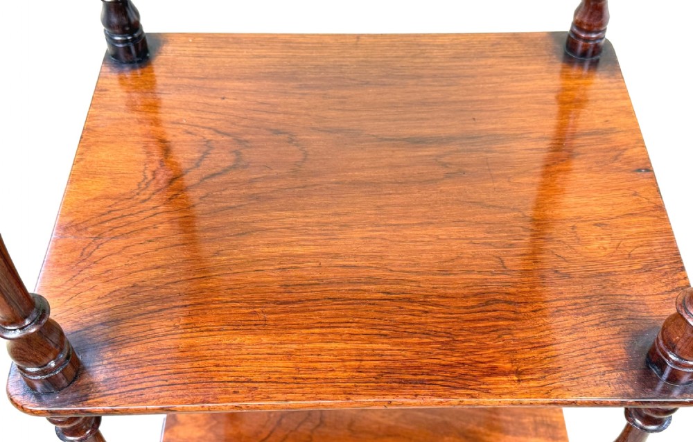A three-tiered 19th-century rosewood whatnot featuring slender turned spindles, top finials, and legs ending in brass castors. View III