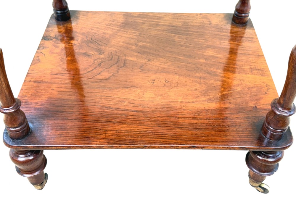 A three-tiered 19th-century rosewood whatnot featuring slender turned spindles, top finials, and legs ending in brass castors. View VI