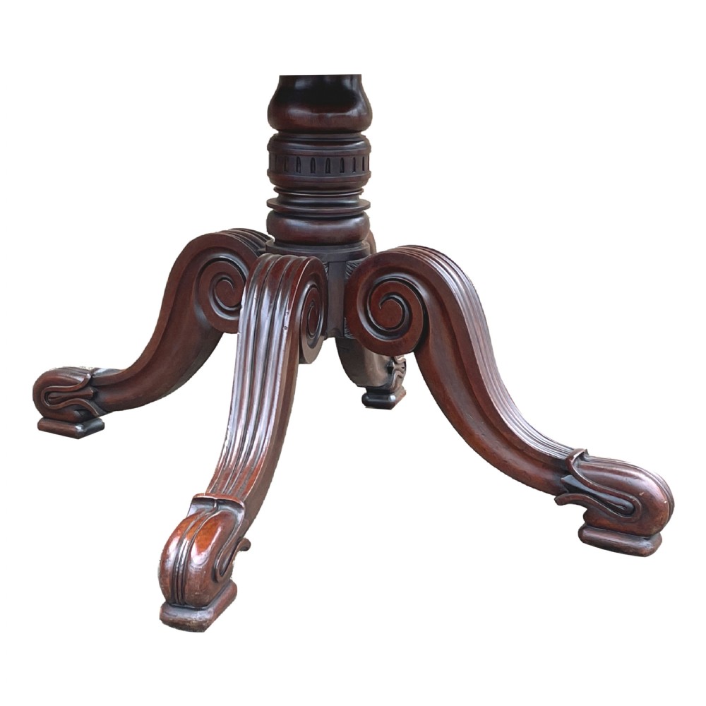 A Regency mahogany twin pillar dining table with an extending centre leaf and carved pedestal supports on brass castors. View II