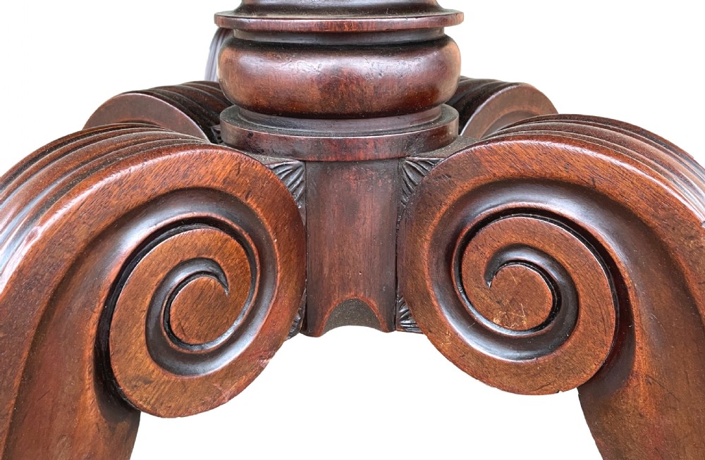 A Regency mahogany twin pillar dining table with an extending centre leaf and carved pedestal supports on brass castors. View III
