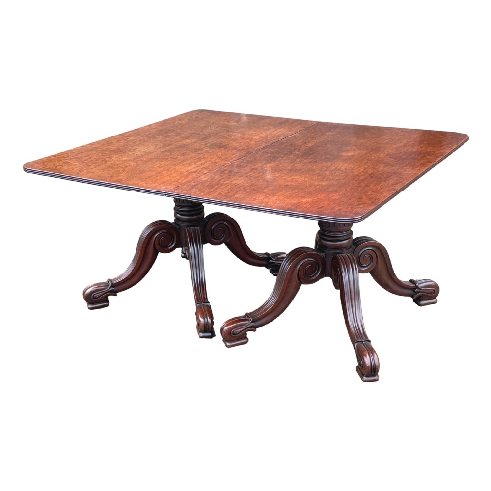 A Regency mahogany twin pillar dining table with an extending centre leaf and carved pedestal supports on brass castors. View IV