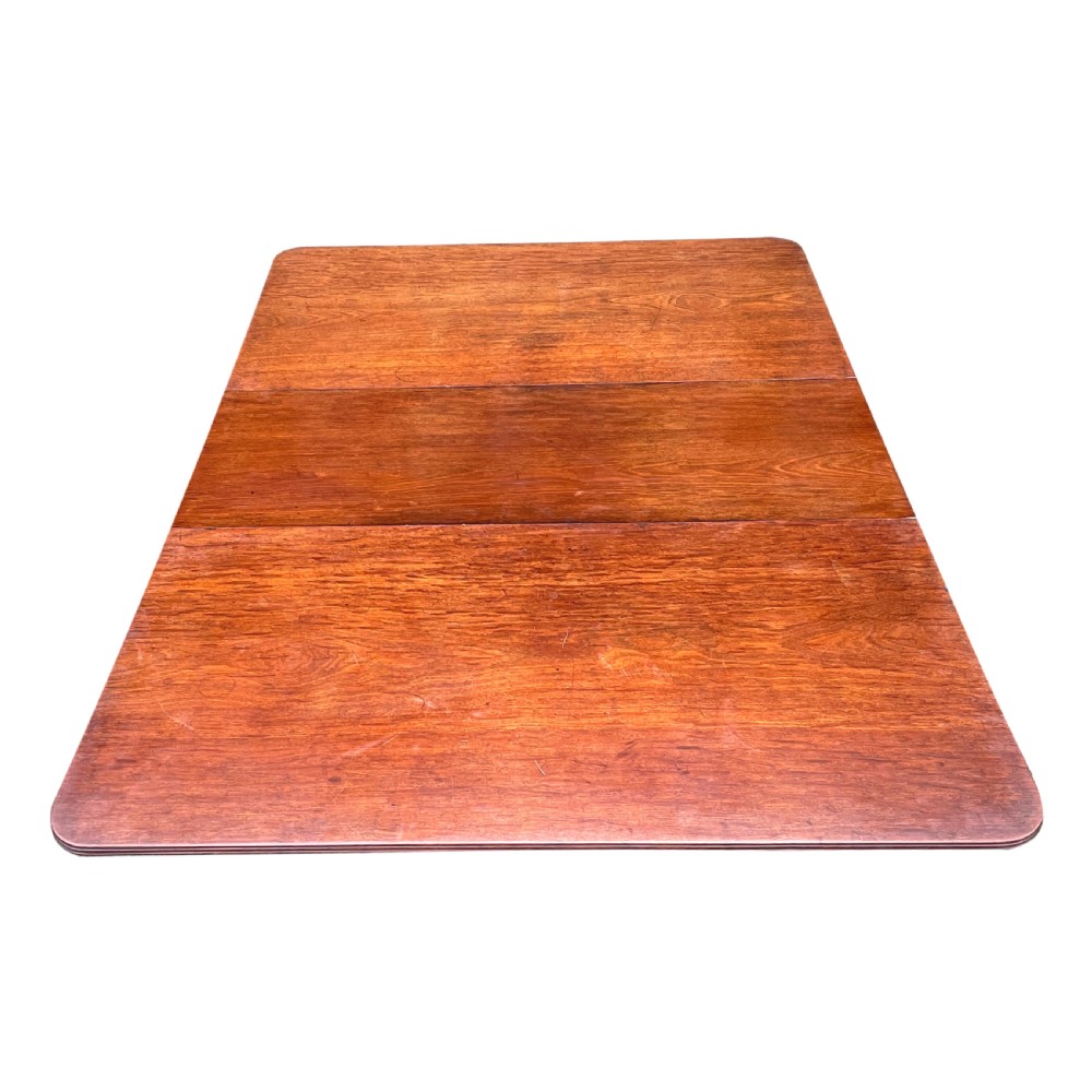 A Regency mahogany twin pillar dining table with an extending centre leaf and carved pedestal supports on brass castors. View VII