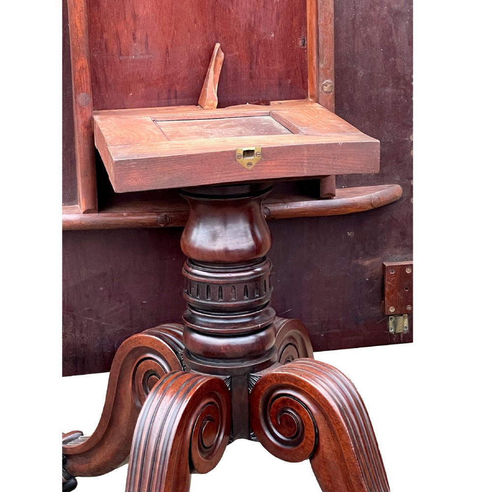 A Regency mahogany twin pillar dining table with an extending centre leaf and carved pedestal supports on brass castors. View X