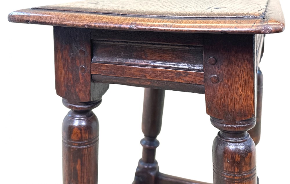 A 17th century rectangular dark oak joint stool featuring turned legs, pegged mortise and tenon joinery, and perimeter stretchers. View VI