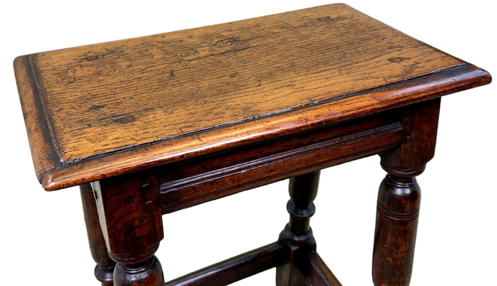 A 17th century rectangular dark oak joint stool featuring turned legs, pegged mortise and tenon joinery, and perimeter stretchers. View VII