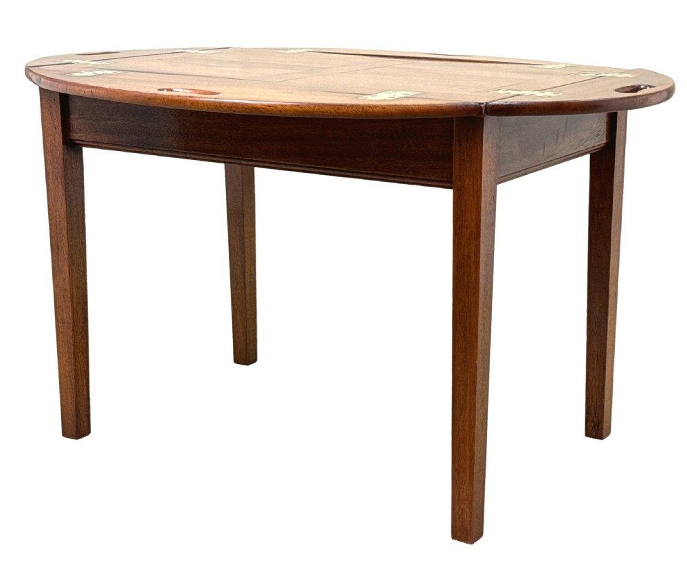 A Georgian mahogany oval butler tray table featuring brass-hinged drop sides with cut-out hand-grips resting on four square legs.